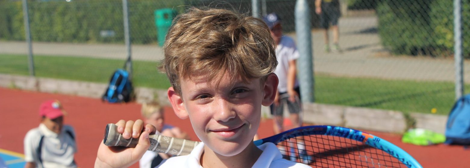 young boy posing for a photo with a tennis racket