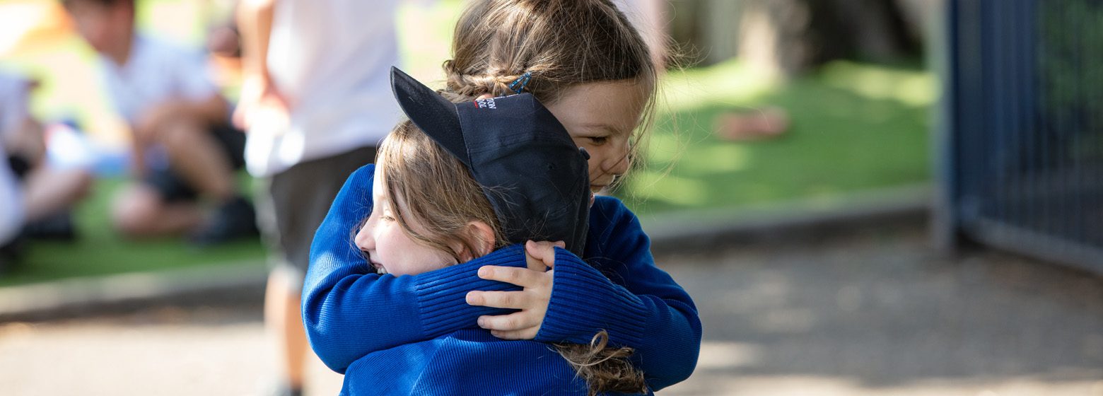 two little girls hugging on the school playground