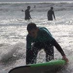 Teenage Boy in Sea Holding a Surf Board