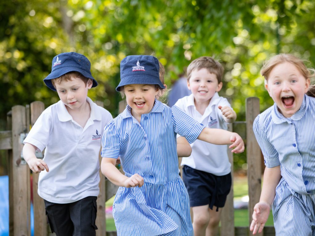Children running across the playground in their uniforms
