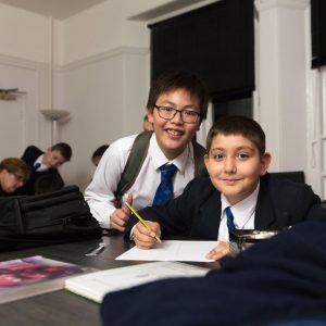 two boys in classroom writing