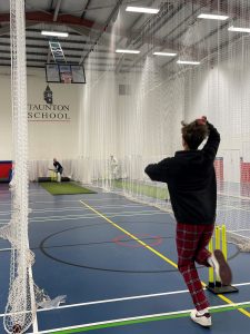 student playing indoor cricket with teacher