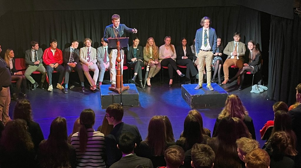 students gathered in theatre for prefect auction